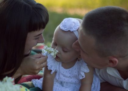 A loving family moment with parents and baby at a sunny outdoor picnic.