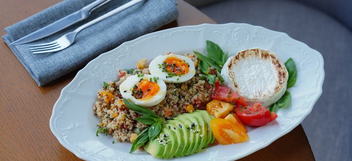 Delicious quinoa salad with sliced avocado, soft-boiled eggs, and fresh herbs.